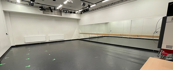 Photo of an empty performance studio, with a wall of mirrors.